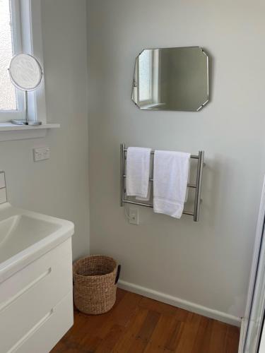 uma casa de banho com toalhas brancas e um espelho em Little Sweetie em Oamaru