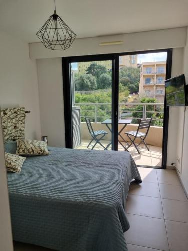 une chambre avec un lit et un balcon avec une table et des chaises dans l'établissement MAGNIFIQUE APPARTEMENT LES PIEDS DANS L'EAU PROPRIANO, à Propriano