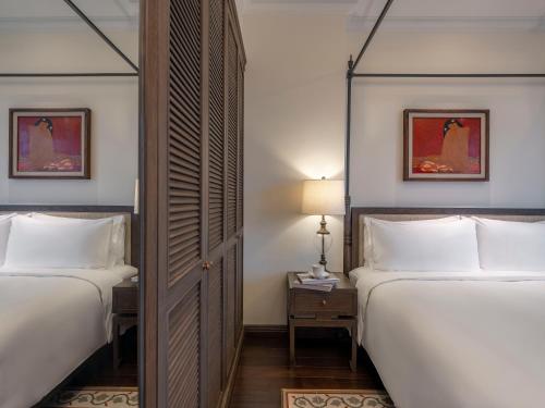 a hotel room with two beds and a mirror at De Syloia Hotel in Hanoi
