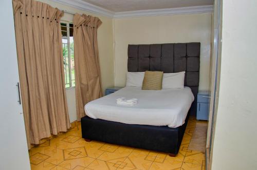 a bedroom with a large bed with a large headboard at Riverstone Guest Lodge in Harare