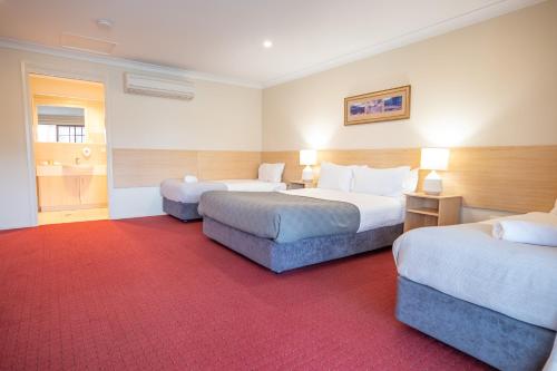 a hotel room with two beds and a red carpet at The Ballandean Pub & Motel in Ballandean