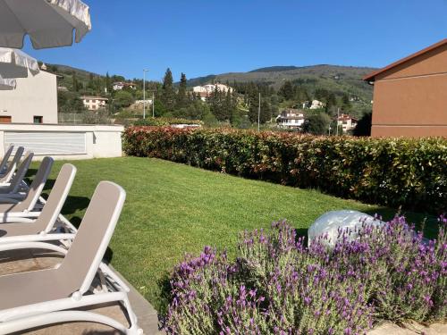 a yard with lawn chairs and purple flowers at The Florence Hills Resort & Wellness in Pelago