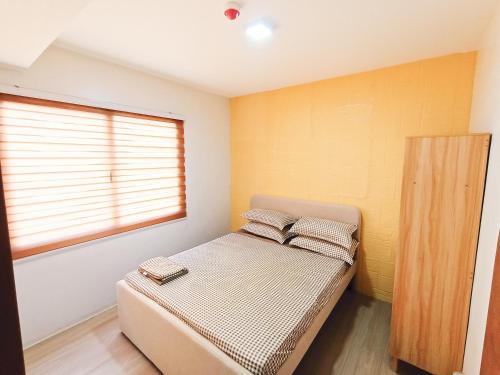 a small bedroom with a bed and a window at The Hive tower D with pool, Wifi, and balcony in Taytay