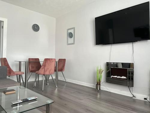 ein Wohnzimmer mit einem Tisch und einem Flachbild-TV in der Unterkunft Spacious 2 Bedroom Flat in Leven, Fife, Near St. Andrews in Fife
