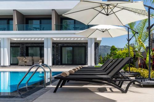 a pair of chairs and an umbrella next to a pool at Edem Villa Diamond in Kemer