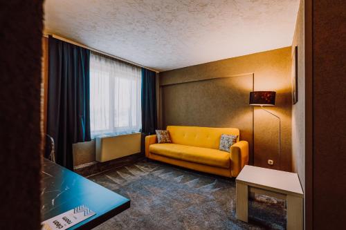 a living room with a yellow couch and a table at HOTEL CIAO in Târgu-Mureş