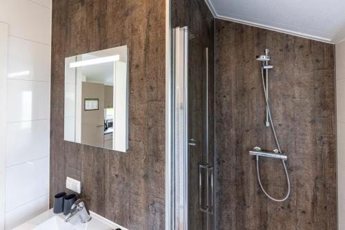 ein Bad mit einer Dusche und einem Spiegel in der Unterkunft Recreatiepark De Bosrand in Oudemirdum