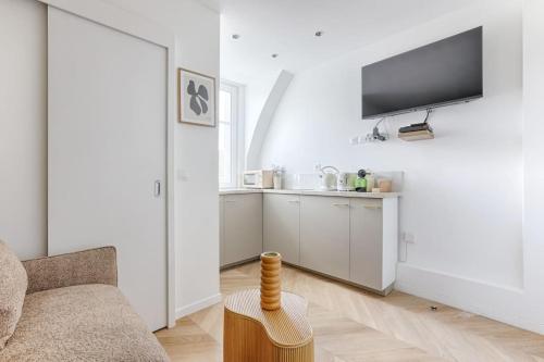 un salon avec un canapé, une télévision et une table dans l'établissement Cosy Studio Théodore Rousseau II, à Paris