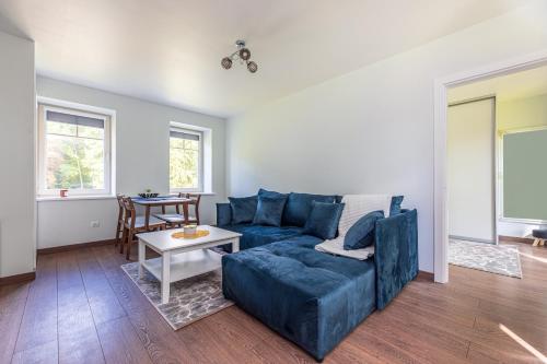 Una sala de estar con un sofá azul y una mesa. en Seaside apartments - Sunset apartment, en Klaipėda