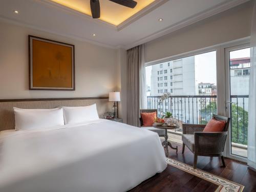 a bedroom with a large white bed and a balcony at De Syloia Hotel in Hanoi