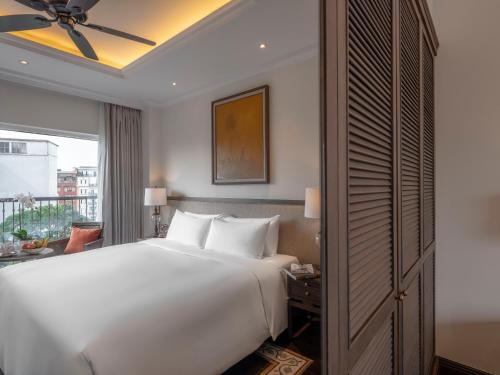 a bedroom with a large white bed and a window at De Syloia Hotel in Hanoi