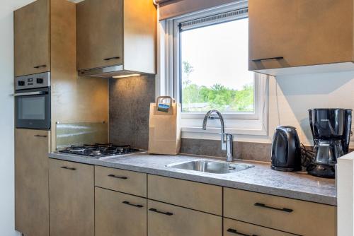 a kitchen with a sink and a window at Recreatiepark De Bosrand in Oudemirdum