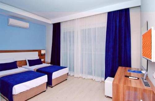 a hotel room with two beds and a television at Kleopatra Ramira Hotel - All Inclusive in Alanya