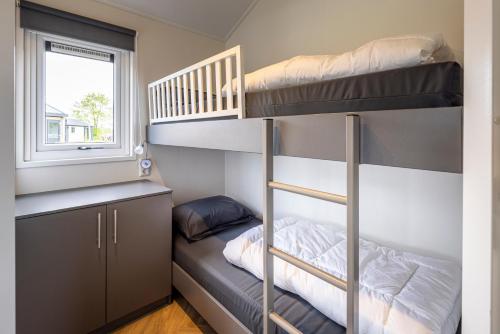 a bunk bed room with two bunk beds and a window at Recreatiepark De Bosrand in Oudemirdum