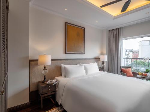 a bedroom with a large white bed and a window at De Syloia Hotel in Hanoi