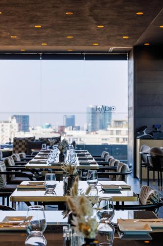 a restaurant with tables and chairs and a large window at ME Milan Il Duca in Milan