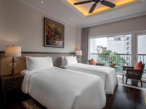 a bedroom with two white beds and a window at De Syloia Hotel in Hanoi