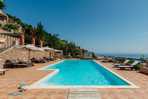 een zwembad met stoelen en uitzicht op de oceaan bij Apelon Tiritas Villas in Leonidion