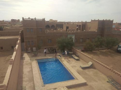 a large swimming pool in front of a building at riad luz merzouga in Merzouga