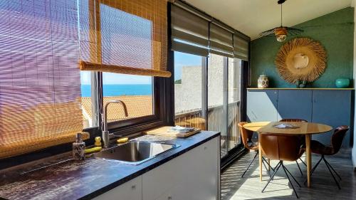 eine Küche mit einem Waschbecken, einem Tisch und einem Fenster in der Unterkunft Sausset-les-Pins, T2 vue sur mer, plage à 200m in Sausset-les-Pins