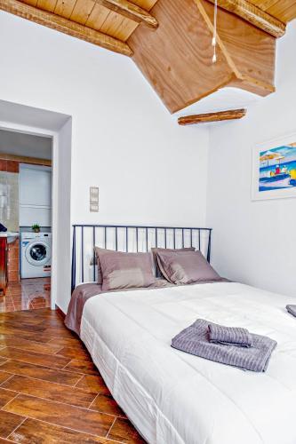 a bedroom with a white bed with a wooden ceiling at La Bella Pietra in Ermoupoli