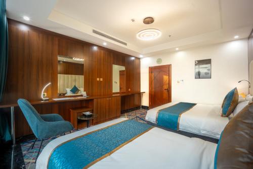a hotel room with two beds and a chair at Donatello Jeddah Hotel in Jeddah