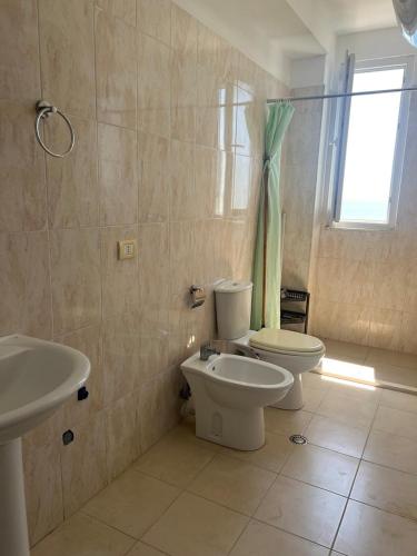 a bathroom with a toilet and a sink and a window at Apartamente ne Shengjin in Shëngjin