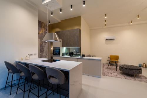 a kitchen with a white counter and some chairs at The Bridge City Luxury Apartments in Zadar