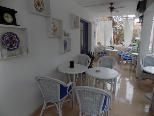 una sala da pranzo con tavoli e sedie bianchi di Hostal Villa Maruja a El Arenal