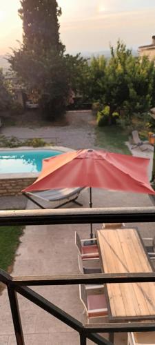 un parasol rouge sur une table à côté d'une piscine dans l'établissement Grande maison de Village, à Villevieille