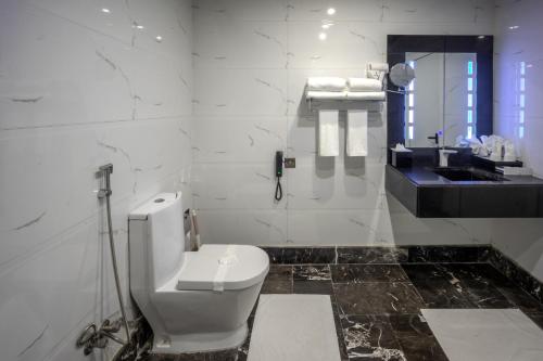 a white bathroom with a toilet and a sink at Donatello Jeddah Hotel in Jeddah