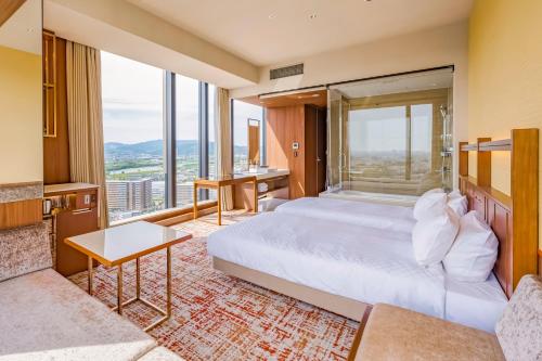 a hotel room with a bed and a large window at Candeo Hotels Osaka Hirakata in Hirakata