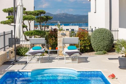 un patio con sillas y una piscina en Luxury apartment Hyperion with private pool and garden, en Murter