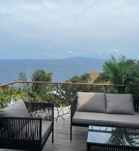 a couch on a balcony with the ocean in the background at Koh Tao studios in Koh Tao