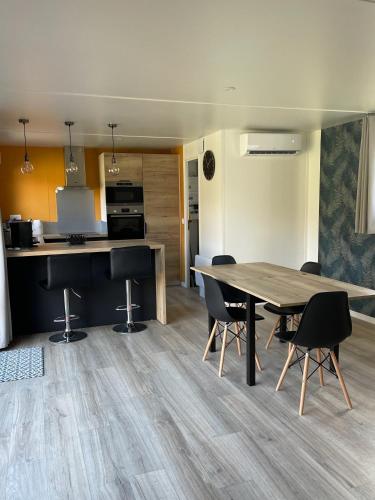 a dining room and kitchen with a table and chairs at Ecolodge 2Ch - Air conditioning - Wifi - Swimming pool and Jacuzzi open all year in Les Mathes