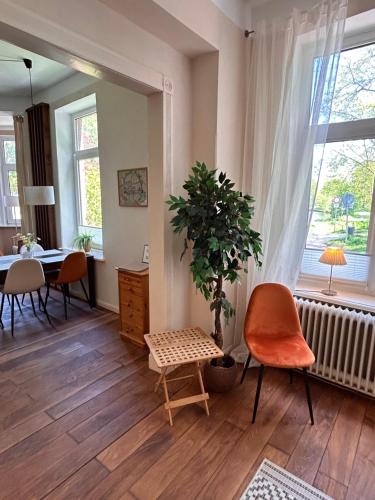 sala de estar con mesa, silla y planta en Schöne Altbauwohnung direkt an der Kesselschleuse! en Emden
