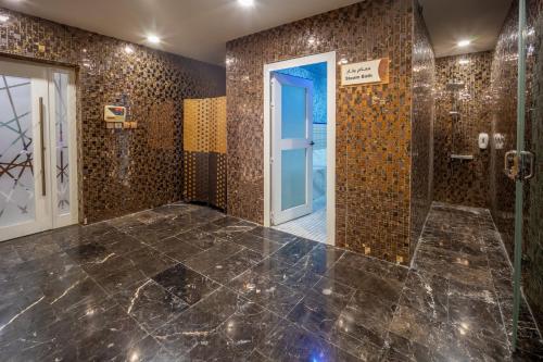 a bathroom with a shower with brown tiles at Donatello Jeddah Hotel in Jeddah
