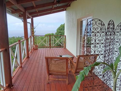 a wooden deck with a table and chairs on it at Vanille & Goyavier in Saint-Philippe