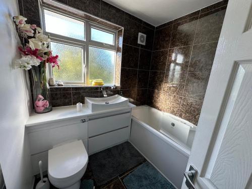 Un baño con inodoro, lavabo y ventana. en Hare&Deer Home Stay, en Hither Green