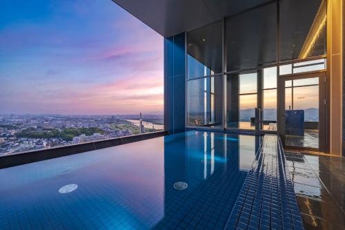 a swimming pool in a building with a view at Candeo Hotels Osaka Hirakata in Hirakata