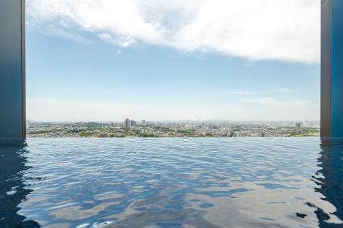 a view of the city from a pool of water at Candeo Hotels Osaka Hirakata in Hirakata