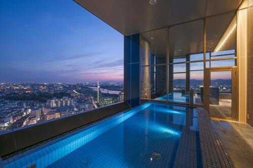 a swimming pool in a building with a view at Candeo Hotels Osaka Hirakata in Hirakata