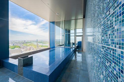 a swimming pool in a building with a view at Candeo Hotels Osaka Hirakata in Hirakata