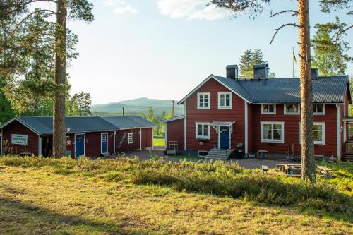 duży czerwony dom z dwoma mniejszymi czerwonymi budynkami w obiekcie Gopshusgården - Rum & Stugor w mieście Mora
