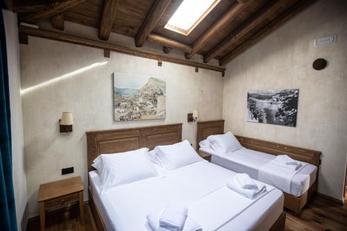 two beds in a room with white sheets at Vista Boutique Hotel in Berat