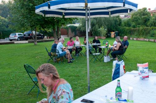 a group of people sitting at tables under an umbrella at La Fattoria Apartments in Lazise