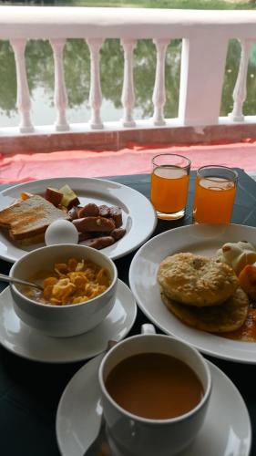 a table topped with plates of breakfast foods and drinks at Damodar River Retreat, Uluberia in Uluberiya