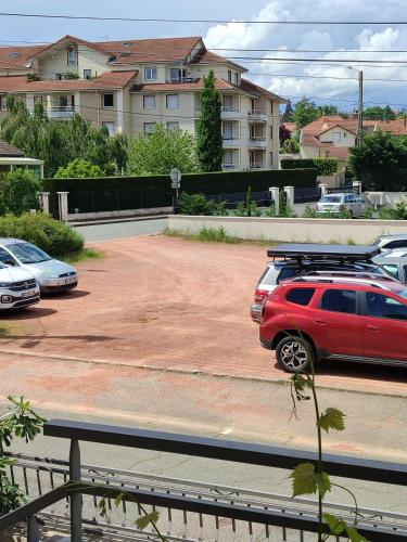 une voiture rouge garée sur un parking avec des voitures garées dans l'établissement Appartement avec Piscine Riorges, à Riorges