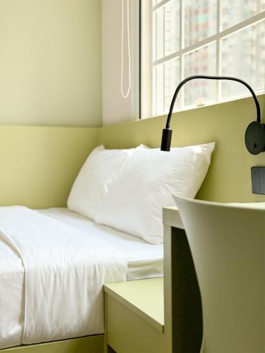 a small bedroom with a bed and a lamp at Urbanwood Hung Hom in Hong Kong