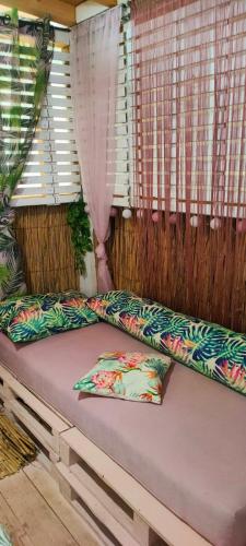 a bed with two pillows sitting in front of a window at каравана ТРОПИК-ЕКЗОТИК А 17 in Sozopol